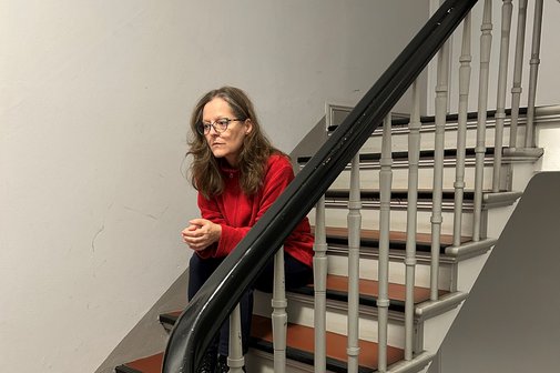 VdK-Mitglied Nicola Bode sitzt auf einer Treppe, ihr Gesichtsausdruck ist niedergeschlagen und erschöpft. 