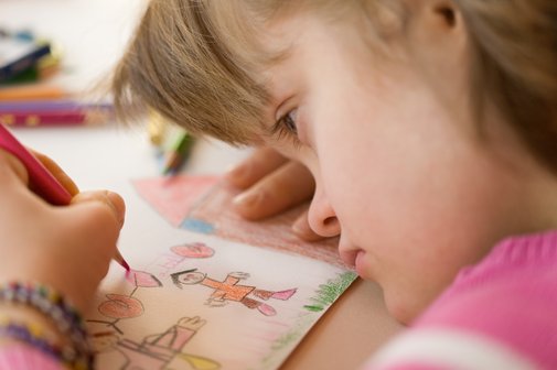 Kind mit Behinderung in der Schule Nahaufnahme eines Mädchens mit Down-Syndrom, das an einem Tisch sitzt und ein Bild malt.