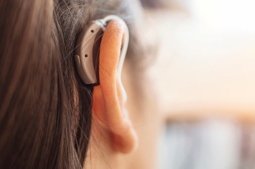 Hörgerät-Versorgung Kopf einer Frau mit einem Hörgerät hinter dem rechten Ohr.