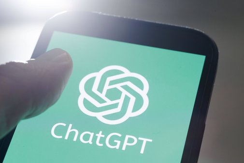 Jemand hält ein Smartphone, auf dem Display sieht man das Logo von ChatGPT
