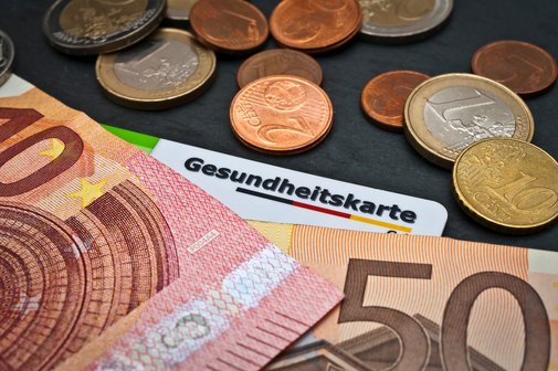 Geldscheine und M&uuml;nzen, darunter liegt eine Gesundheitskarte.