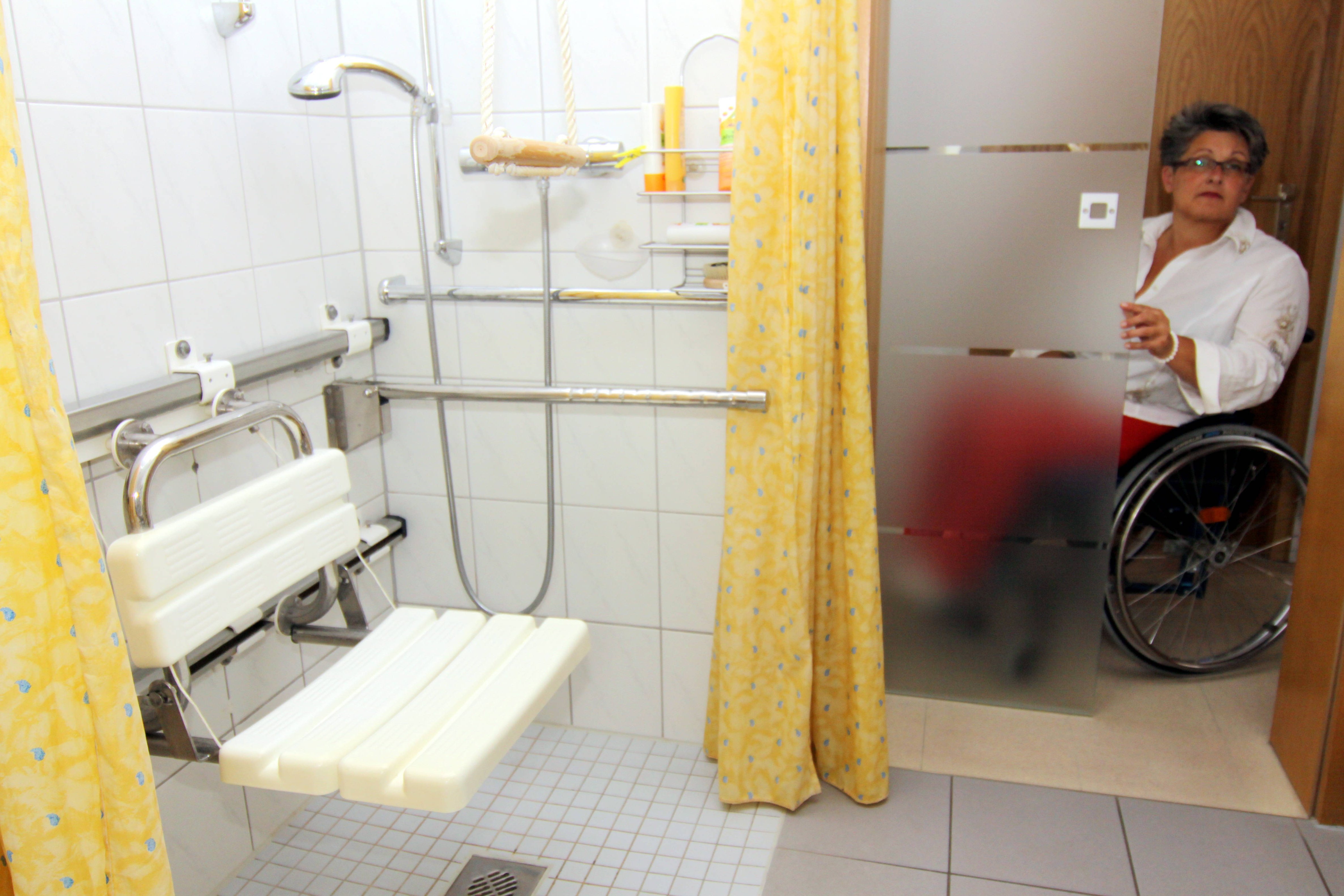 Seniorengerechte Wohnung Frau im Rollstuhl an der Tür zu ihrem barrierefreien Badezimmer