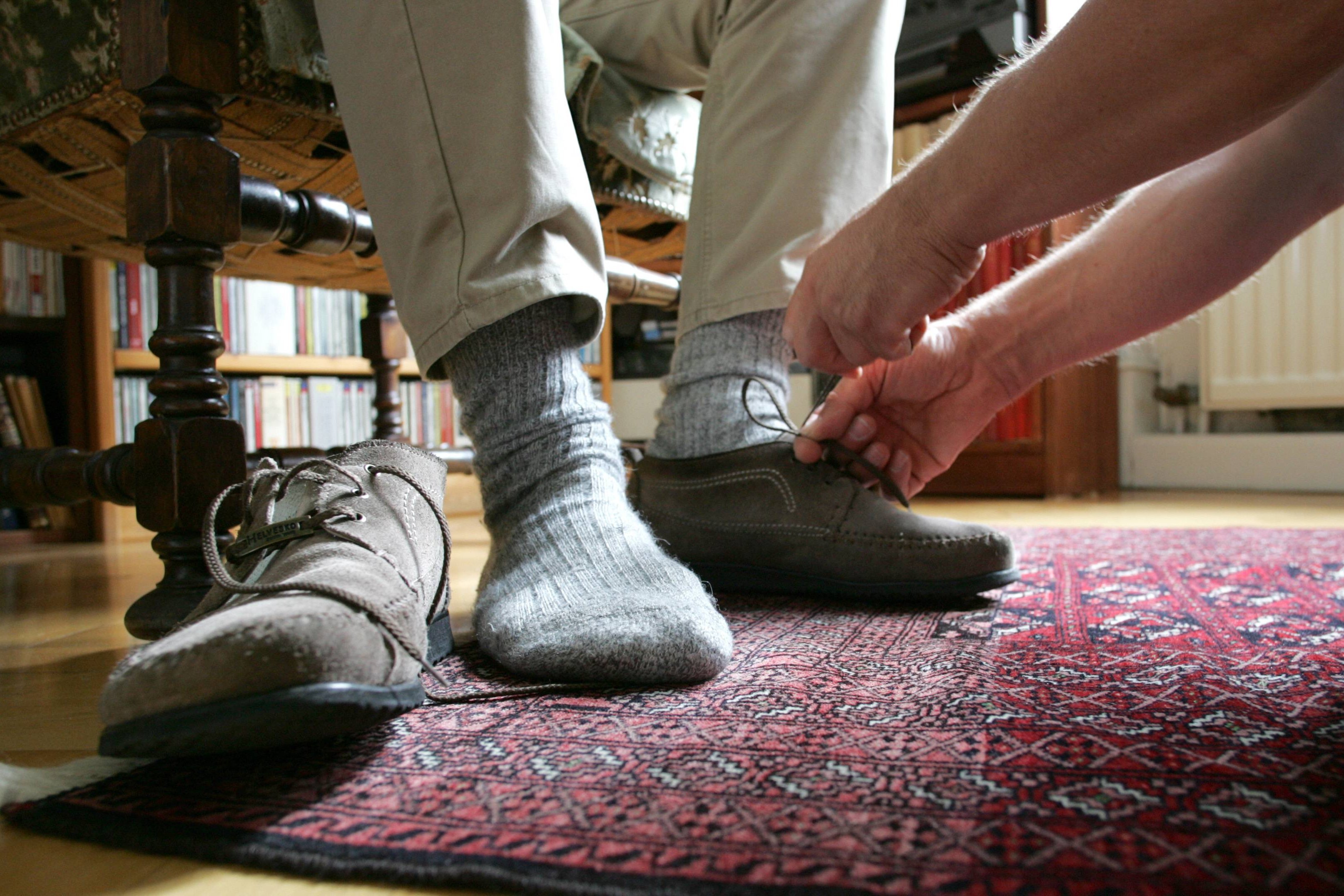 Pflege zuhause Eine Frau hilft einem Mann beim Anziehen der Schuhe
