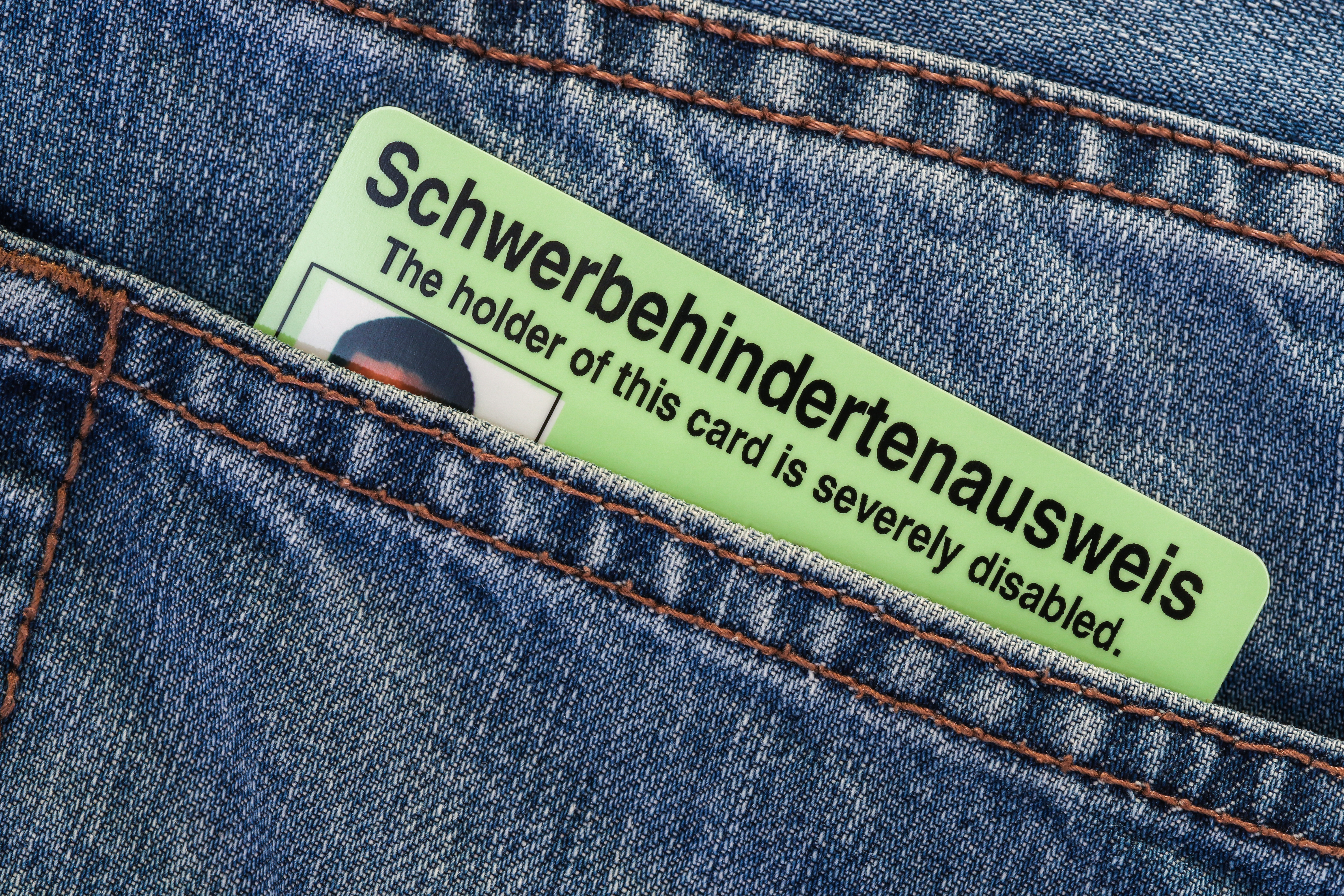 Eine hintere Jeanstasche, aus der ein Schwerbehindertenausweis im Scheckkartenformat herausschaut.